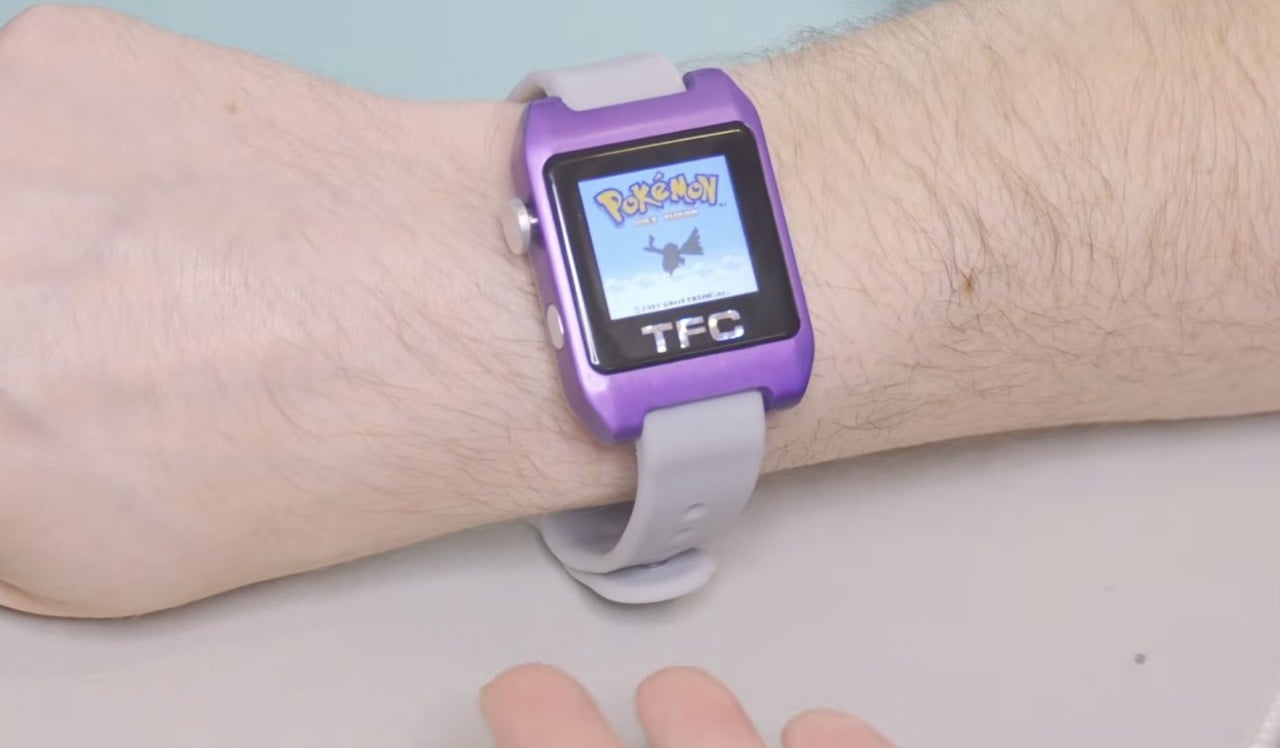 A tiny wrist-worn Game Boy Color style device with miniature game cartridges